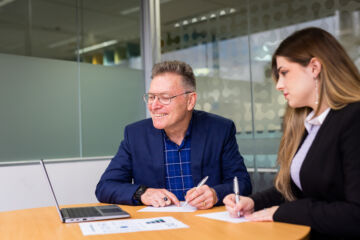 eWorks eLearning Process two staff writing and looking at laptop monitor