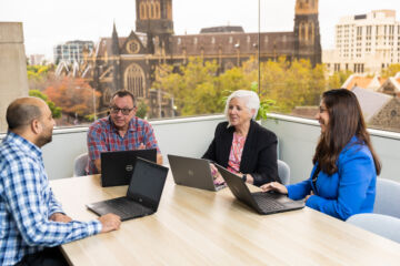 eWorks Team of Experts with four people in a meeting room with large windows