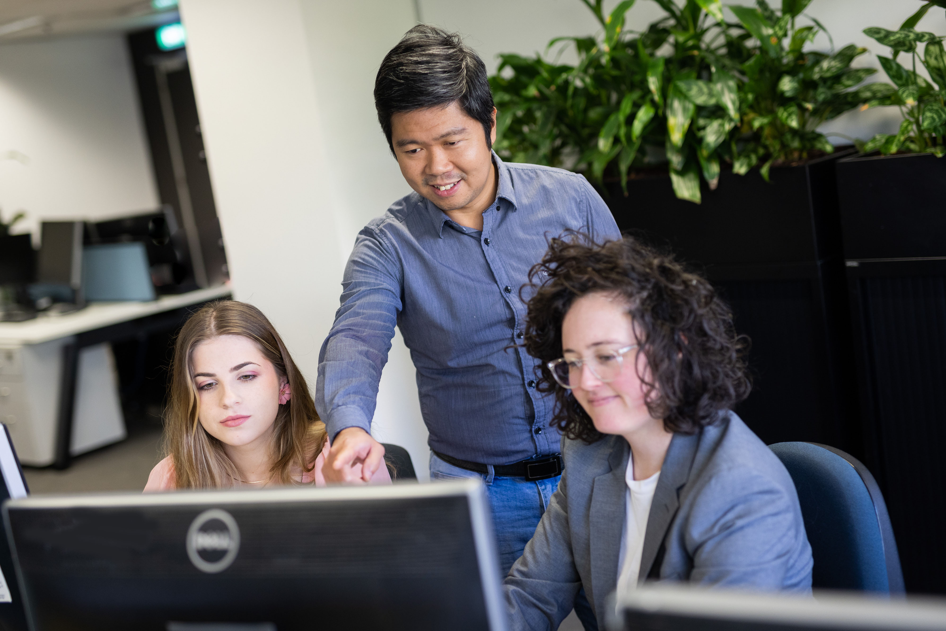 eWorks LMS Benefits 3 staff at a computer looking at a monitor