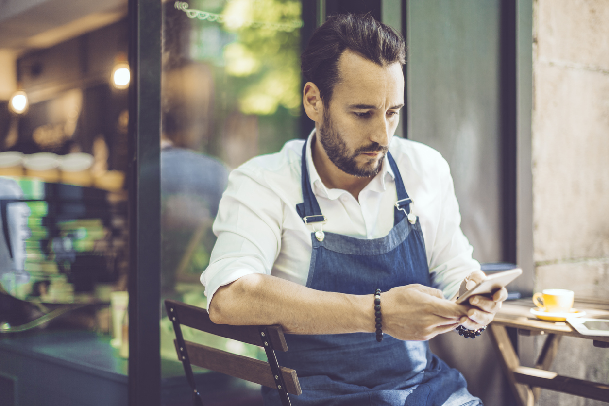 Cafe waiter doing training module on mobile phone hospitality training